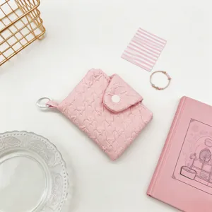 Detailansicht einer süßen rosa gefalteten Mini-Geldbörse mit Druckknopf und weißem Clip.