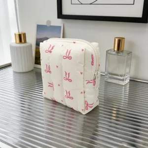 Detalle de la bolsa de maquillaje acolchada crema con un lindo patrón de lazo rosa