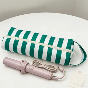 Grande astuccio da viaggio a righe bianche e verdi con un ferro arricciacapelli rosa