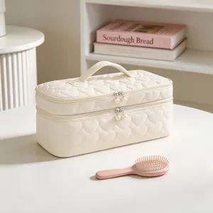 Detail view of creamy white heart-quilted travel makeup bag featuring pearl zipper pulls