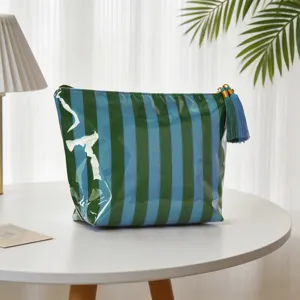 Detailansicht einer gestreiften PVC-Kosmetiktasche mit einer dekorativen Quaste.