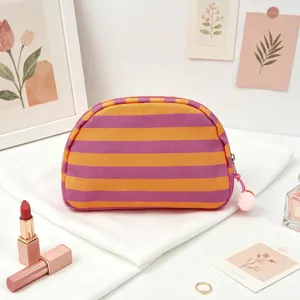Macro view of a vibrant orange and purple striped shell-shaped makeup bag with charm