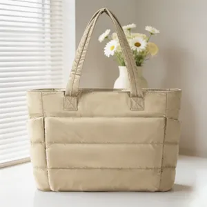 Vue complète de l'élégant sac cabas matelassé champagne placé près d'une fenêtre