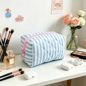 Detailed macro view of quilted blue striped makeup bag on a desk with beauty accessories