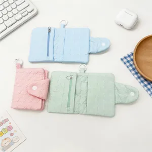 Drei strukturierte Mini-Geldbörsen in Pastellblau, Rosa und Minzgrün mit Druckknopf.