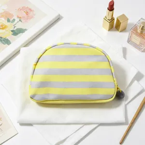 Close-up of yellow and gray striped shell cosmetic bag with a cute pom-pom zipper pull