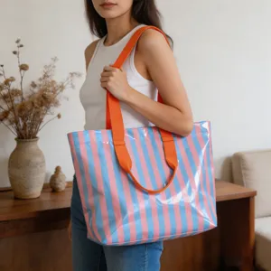 Grande borsa tote in PVC a righe con manici arancioni portata a spalla da una donna