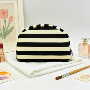 Elegant black and white striped shell cosmetic bag with a decorative tassel and pom-pom