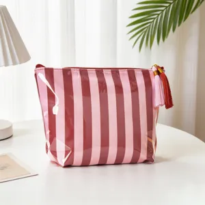 Detail einer gestreiften wasserdichten PVC-Kosmetiktasche mit einer rosa Quaste
