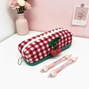 Close-up detail of red and white plaid wool storage pouch with 3D crochet cherry.