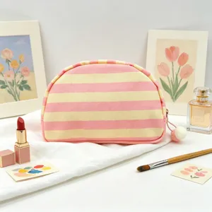 Detail view of pink and yellow striped canvas makeup bag with soft pom-pom zipper pull