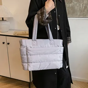 Détail d'un sac cabas matelassé léger tenu à la main, texture douce rembourrée