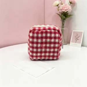 Detail view showing the soft plush texture and red checkered pattern of the storage pouch.