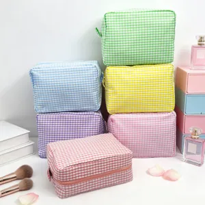 Stack of colorful gingham seersucker cosmetic bags for travel storage in pastel colors