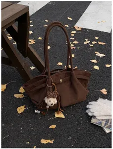 Braune Wildleder-Einkaufstasche mit Teddybär-Anhänger im Herbst