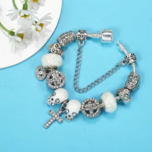 Punk style charm bracelet with luminous skulls and cross pendant on blue background.