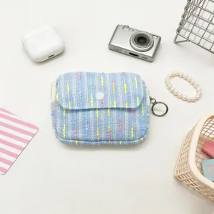 Mini blue tweed coin purse with white button flap closure for portable makeup storage