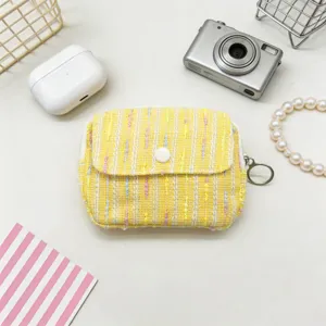 Detailed view of a yellow tweed mini coin purse with a button flap and ring zipper pull.