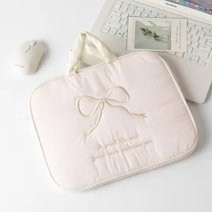 Vista superior de funda rosa acolchada para portátil con lazo bordado y frase.