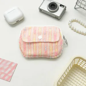 Close-up of pink tweed flap mini storage bag for lipstick and coins with lifestyle props