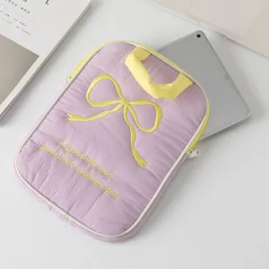 Detalle de una funda de tableta morada con bordado de lazo amarillo y texto decorativo