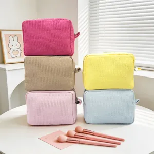 Detalle de varias bolsas de cosméticos con textura de gofre y brochas de maquillaje