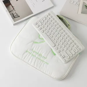 Vista detallada de la funda blanca para portátil con bordado de lazo verde y eslogan