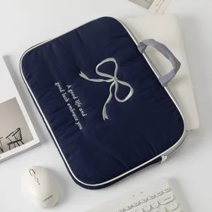 Detalle de una funda para portátil azul marino con lazo bordado y texto en blanco