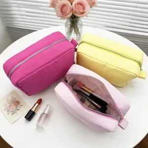 Vista detallada de bolsas de maquillaje con textura de gofre en rosa y amarillo con accesorios