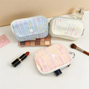 Detailed view of mini portable tweed makeup pouches in pastel blue, cream, and pink colors.