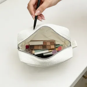 Vista detallada del interior de un neceser blanco de gofre con productos de belleza