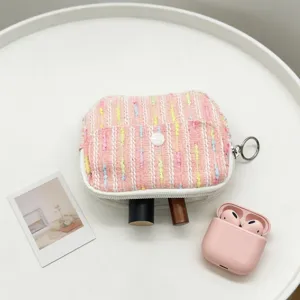 Close-up view of a pink tweed mini coin pouch used for storing lipstick and wireless earbuds