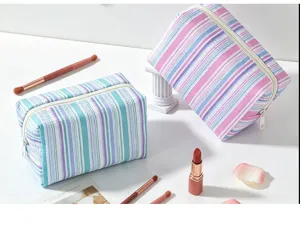 Detail shot of striped seersucker cosmetic bags in blue and pink tones