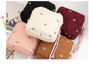 Set of quilted bow embroidery storage pouches in pink, cream, burgundy, and brown.