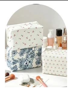 Detailansicht von Cord-Kosmetiktaschen mit Blumen- und Kirschmuster und Make-up