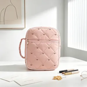 Bolsa organizadora rosa acolchada con lazos bordados sobre una mesa minimalista