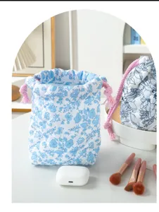 Close-up detail of a blue floral quilted drawstring makeup bag with soft pink ropes
