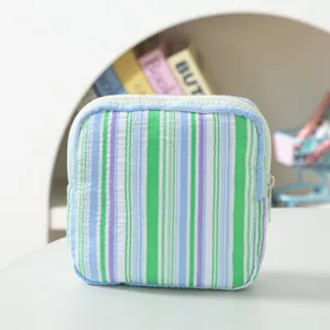 Close-up view of the portable seersucker striped pouch featuring a secure white zipper closure