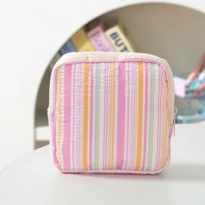 Macro view showing the textured pink striped seersucker material on a square pouch bag.