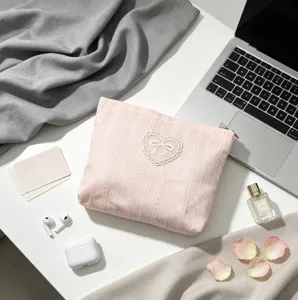 Macro detail of a soft pink lace bow cosmetic bag on a stylish lifestyle desk setup.