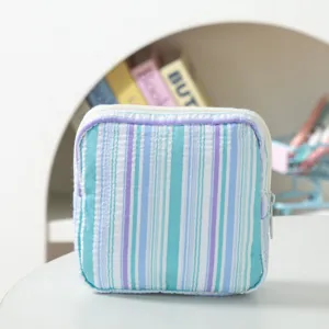 Detailed view of square striped seersucker pouch with white zipper for small items