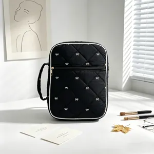 Vista detallada de bolsa de almacenamiento acolchada negra con motivos de lazos blancos.