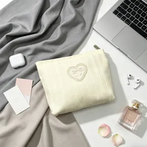 Elegant cream makeup bag with heart embroidery and bow detail shown in lifestyle setting