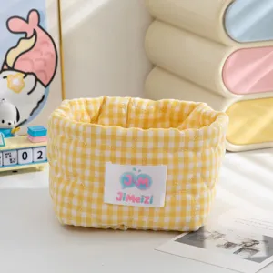 Gros plan d'un panier de rangement en tissu matelassé à carreaux jaunes pour le bureau