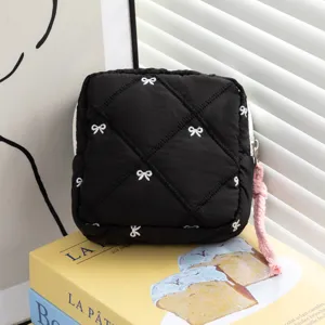 Detailed view of the black quilted pouch with embroidered white bowties.