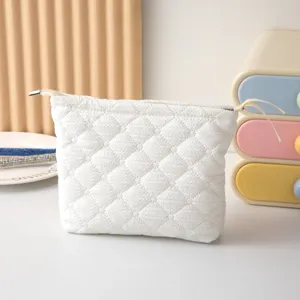 Detalle de neceser blanco acolchado con diseño de diamantes y cierre de cremallera