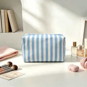 Gros plan d'une trousse de maquillage en seersucker à rayures bleues et blanches sur une coiffeuse