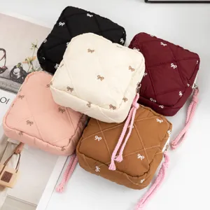 Detailed view of five colorful quilted bow cosmetic pouches with braided zipper pulls