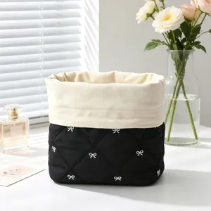 Close-up of a quilted black cosmetic bag with white bow patterns and drawstring closure