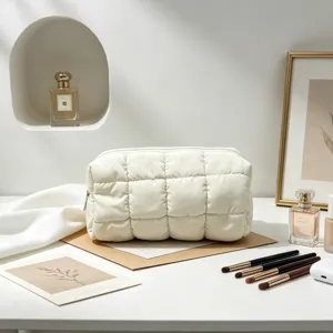 Detalle de un neceser acolchado blanco en un entorno de estilo de vida minimalista.